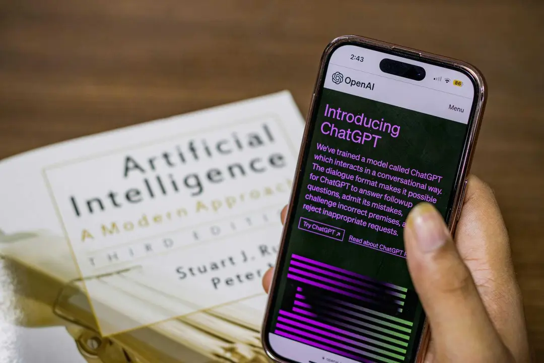 Tel&eacute;fono m&oacute;vil con informaci&oacute;n sobre inteligencia artificial junto a un libro especializado en la materia.