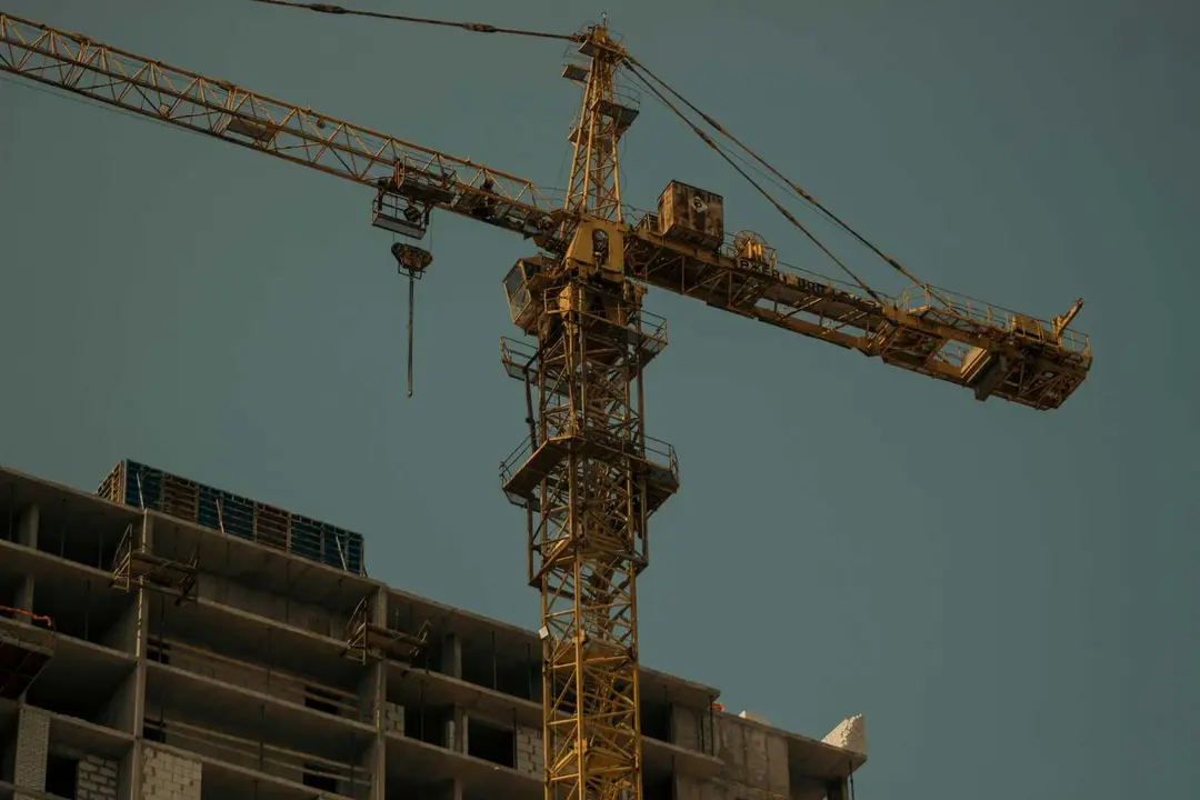 Gr&uacute;a en funcionamiento junto a una estructura residencial en construcci&oacute;n en un entorno urbano
