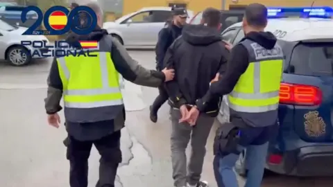 Agentes de la Policía Local conducen al vehículo a uno de los detenidos