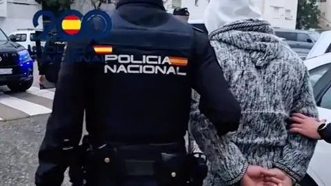 Uno de los detenidos, acompañado por el agente de la Policía