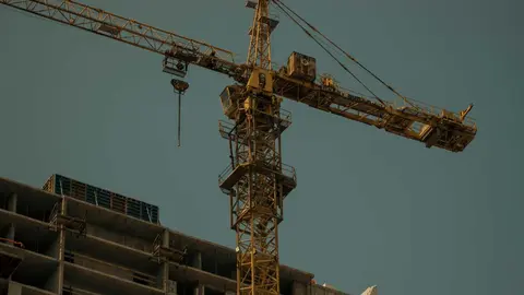 Gr&uacute;a en funcionamiento junto a una estructura residencial en construcci&oacute;n en un entorno urbano