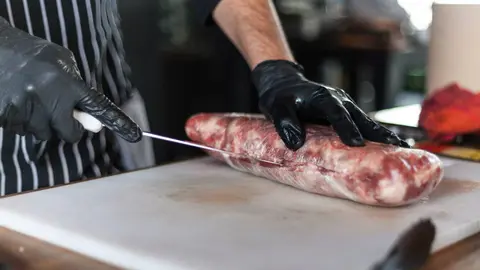 Un profesional atiende una carnicer&iacute;a tradicional en un mercado espa&ntilde;ol