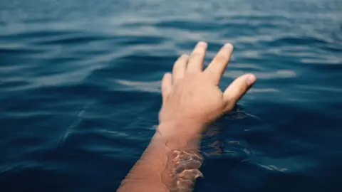 Una mano emerge del agua durante una situaci&oacute;n de emergencia en el mar